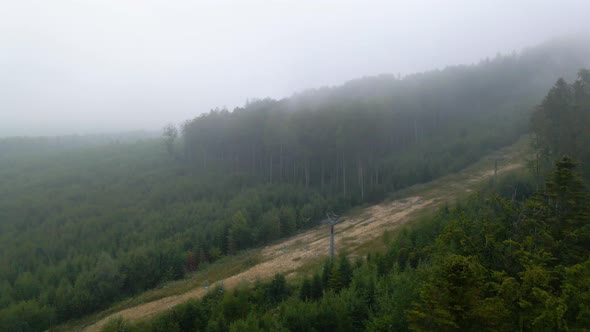 Aerial view over foggy forest and a road, on a mysterious, moody day, in the Carphatian mountains, U