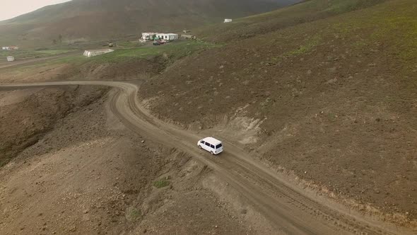 Aerial view of a family van car on a curvy and dirt road in Fuerteventura.