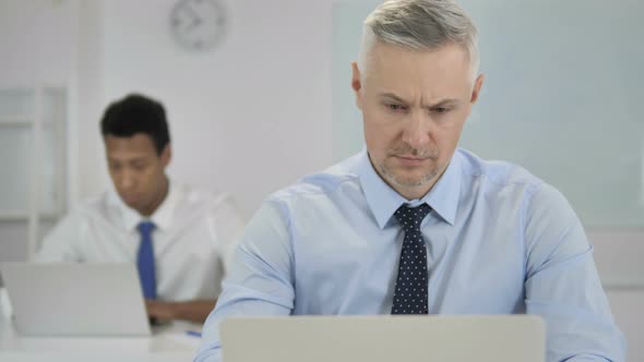 Pensive Grey Hair Businessman Thinking and Working on Laptop