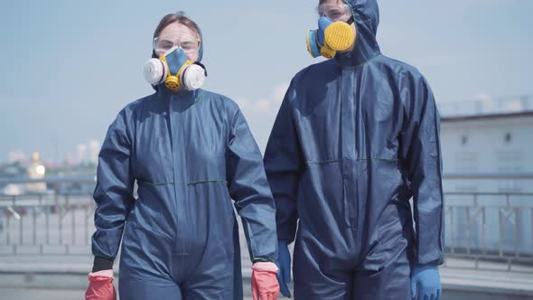 Young Couple Dating Outdoors in Chemical Suits and Respirators. Portrait of Beautiful Woman and