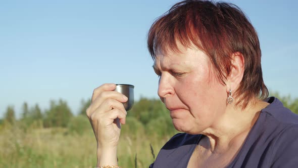 A Lady Happily Chatting While Sipping the Water