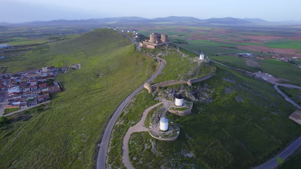 Aerial top view of ancient windmills and medieval fortress hill top above Consuegra town, Spain.