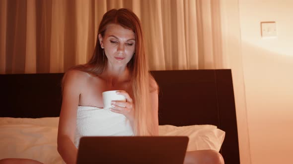 Tired Woman Using Laptop on Bed During Evening Time