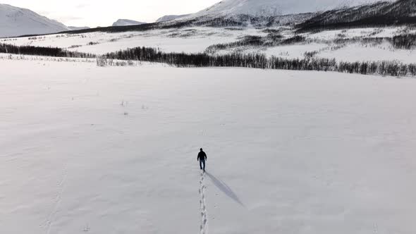 Man Walking In Immaculate Snow In Snowy Scandinavian Valley, Aerial