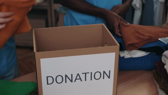 Diverse Colleagues Putting Clothes Into the Cupboard Box While Working at the Donation Center