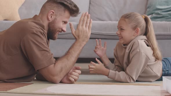 Father and Little Daughter Arm Wrestling at Home