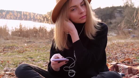 Slow Motion Caucasian Blonde Woman with Beige Hat in Black Sweater Use Phone and Listen Music