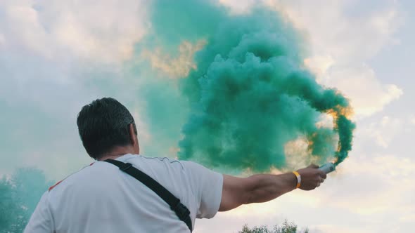 Colorful Smoke Flares Against the Sky. Slow Motion. Man Holding Smoke Bomb