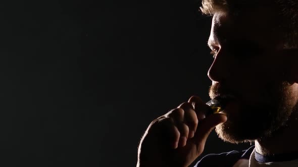 Guy Smokes an Electronic Cigarette and Exhales a Lot of Smoke. Black Background