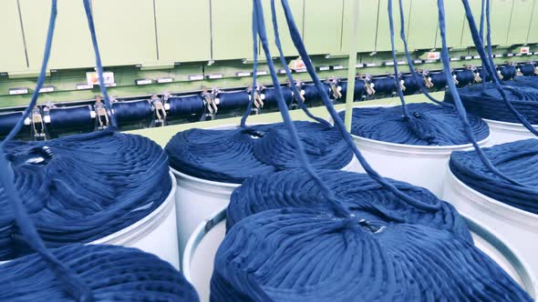 Machinery Complex is Unreeling Coils of Blue Yarn