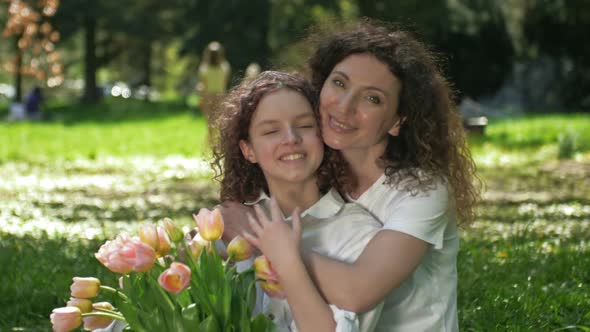 Portrait of a Woman Hugging Her Teenage Daughter with a Bouquet of Tulips