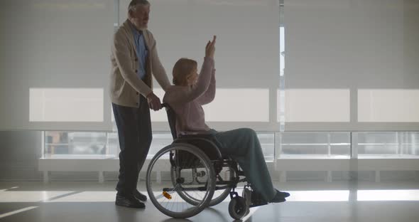 Senior Man Pushing Wheelchair with Wife Sitting and Dancing