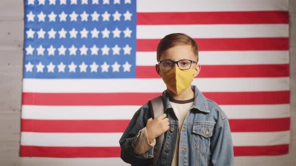 Schoolboy in Face Mask Posing on American Flag in Studio