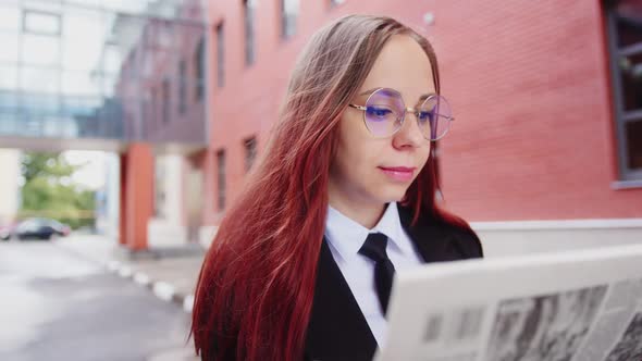 Thoughtful Young Woman Reading Newspaper on Street