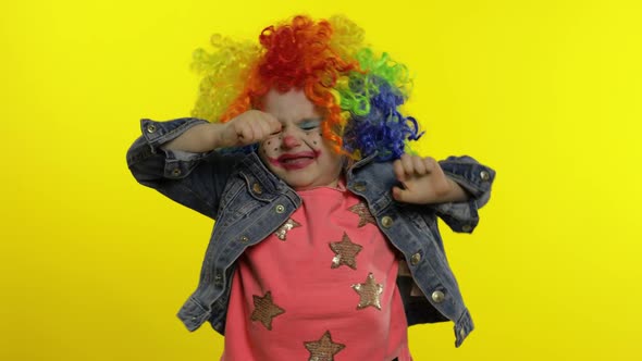 Angry Little Child Girl Clown in Colorful Wig Making Evil Faces. Shows Fist. Halloween. Expressions