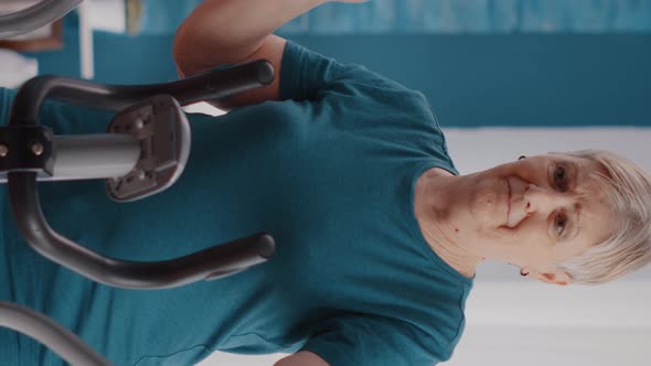 Vertical Video Close Up of Retired Woman Riding Stationary Bicycle at Home