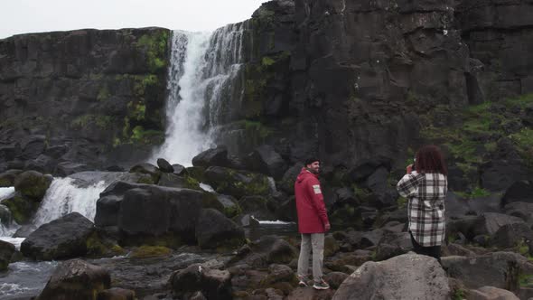 Couple Filming Towards Oxararfoss Waterfall