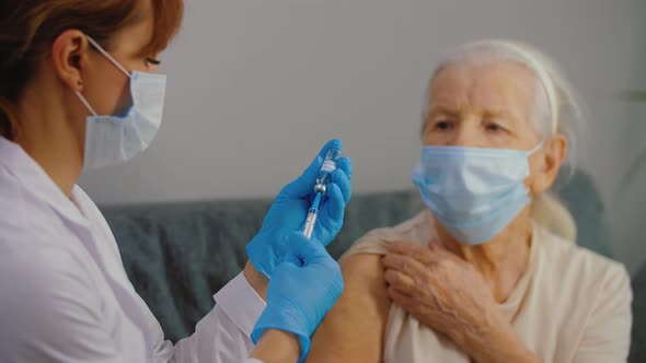 Medical Nurse Doing Injection of Coronavirus Vaccine to Senior Woman