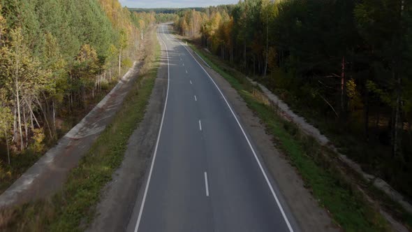 Asphalt road with traffic cars between forest in Ural