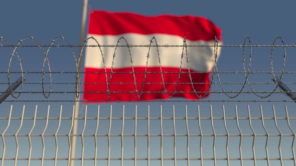 Waving Flag of Austria Behind Barbed Wire Fence