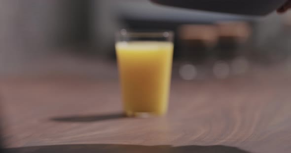 Slow Motion Man Put Blue Boawl with Pesto Fettuccine on Walnut Table with Orange Juice