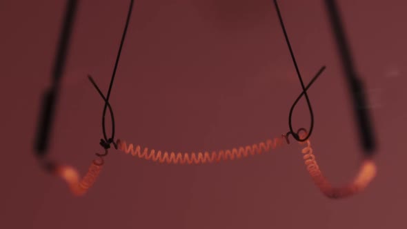 The Tungsten Filament in a Glass Lamp Closeup in Slow Motion on Red Background