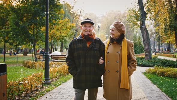 Happy Couple Grandparents in Elegant Outerwear are Talking and Smiling During Romantic Walk in
