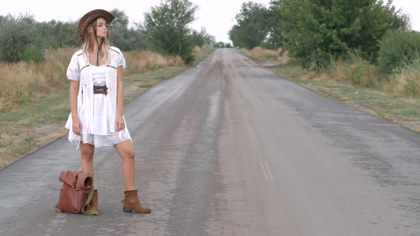 Hipster hitchhiker tourist traveler woman with backpack on the long road, stop car.