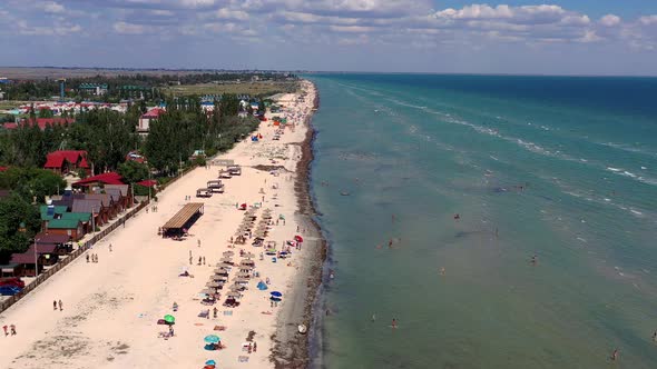 Beautiful flight in summer over the beach. People are resting near the sea.