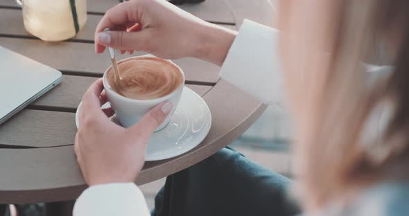 Woman stirs coffee while at table