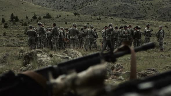 Panning shot of soldiers at the end of mortar training with packs and gear.