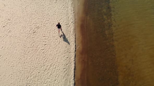 Male with Dog Runs Along the Beach