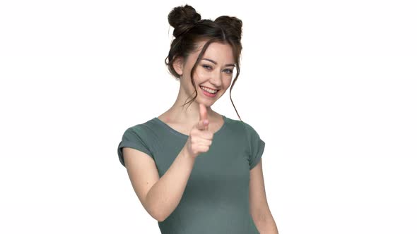 Portrait of Young Woman with Double Buns Hairstyle Gesturing Finger on Camera with Smile Meaning Hey