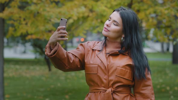 Closeup Young Hispanic Woman Stands in Autumn Park Holding Phone in Hand Girl Blogger Posing