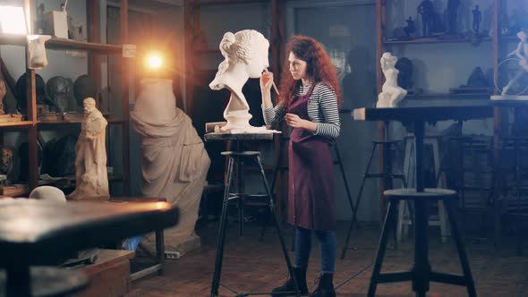 A Lady is Brushing a Gypsum Bust in a Studio