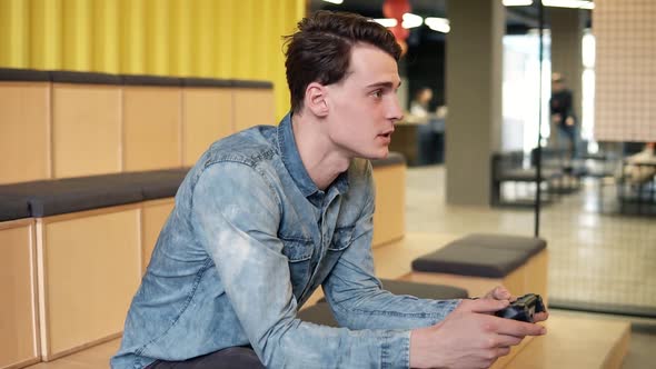 Attractive Sexy Young Guy in Denim Shirt Playing Video Games with Sincere Excitement