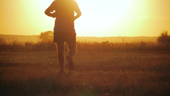 Running Man Silhouette in Sunset Time. Outdoor Cross-country Running. Athletic Young Man Is Running