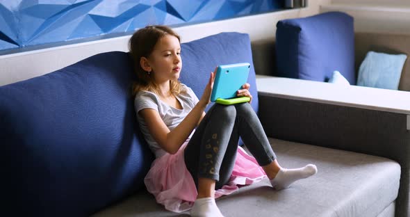 Cute Little Girl Sitting on Couch Kid Addicted to Technology Enjoying Playing Online Game on Digital