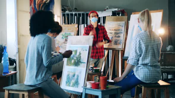 Art Teacher in a Face Mask is Explaining Paintings to His Students