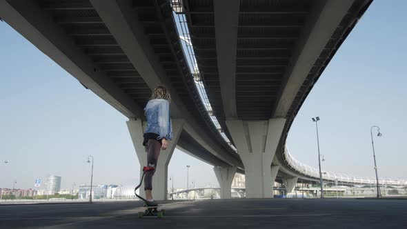 Stylish Man with Leg Prosthesis Skates Board Under Bridge