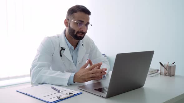 Indian Cheerful Male Doctor in Hospital Consulting Using Pc Laptop Computer