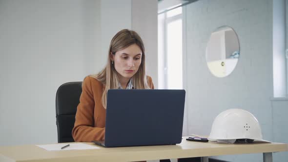 Portrait of Confident American Businesswoman Working with Laptop at Table in Workspace