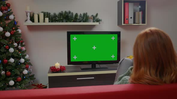A girl watching Green Screen Mockup TV in a Chrismas decorated living room.