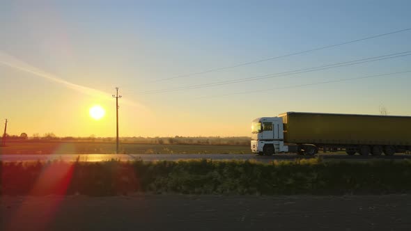 Aerial View of Semitruck with Cargo Trailer Driving on Highway Hauling Goods in Evening