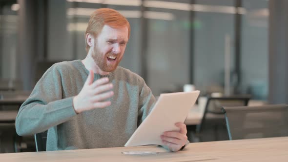 Young Man Upset While Reading Documents in Office