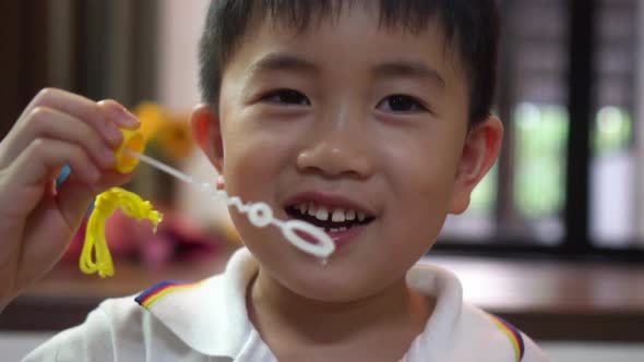 Little Boy Blowing Bubbles and Smiling at Home