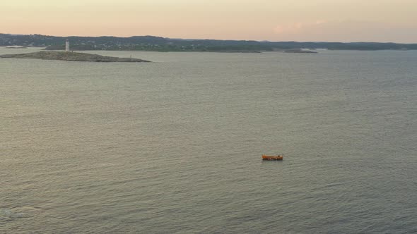Yellow Boat Sailing At The Seascape With A Distant View Of Lille Torungen Lighthouse In Agder County