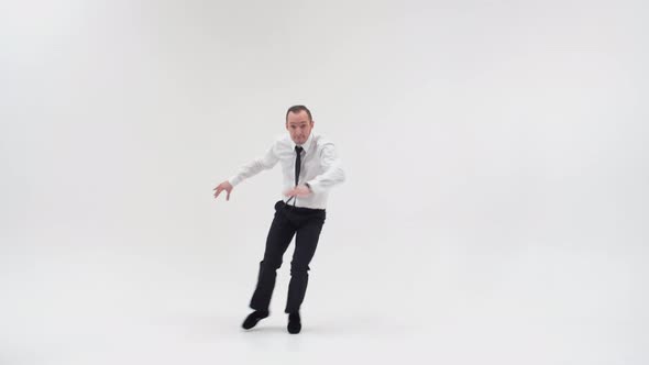 A dancer in office clothes makes small jumps, bounces high, spreading his legs and pointing his fing