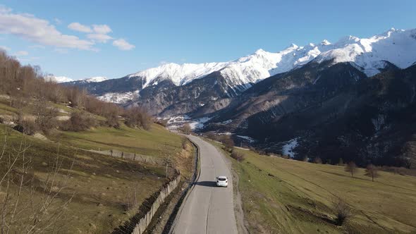 Drone aerial view. Car on the road between mountains. Caucasus, Georgia and Sunny weather.