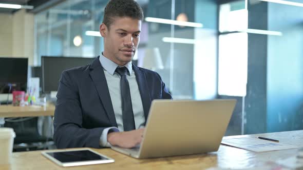 African Businessman Using Laptop in Modern Office